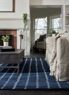 a living room filled with furniture and a blue rug on top of a hard wood floor