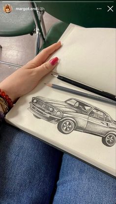 a woman's hand is holding a drawing of a car