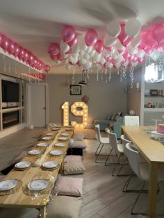 a long table with plates and balloons hanging from it's ceiling in a room