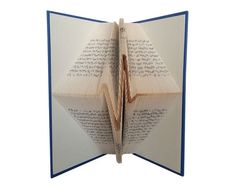 an open book with pages folded in the shape of a triangle and writing on it