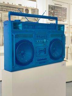 a blue boombox sitting on top of a white pedestal in front of a wall