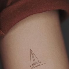 a small sailboat tattoo on the back of a woman's left thigh,