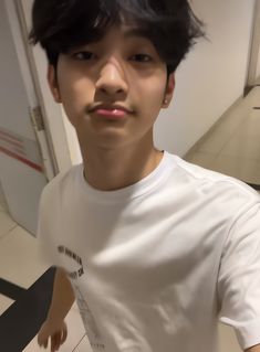 a young man in a white t - shirt is taking a selfie