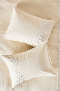 two white pillows sitting on top of a bed