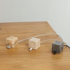 three cubes connected to wires on a wooden table