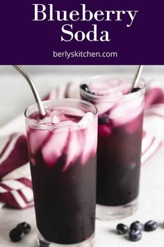 two glasses filled with blueberry soda on top of a table