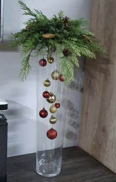 a vase filled with christmas ornaments on top of a wooden table next to a wall