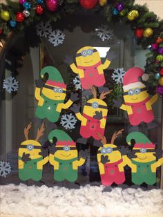 christmas decorations made out of construction paper are displayed in front of a glass window with snowflakes and minion figures