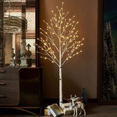 a small white tree with lights on it next to a dresser