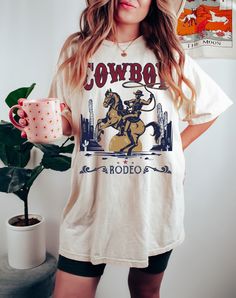 Embrace the spirit of the Wild West with our Vintage Western Cowboy Graphic T-Shirt. Perfect for those who love the rugged charm of cowboy culture and retro fashion, this shirt is a must-have for any wardrobe. Features: Vintage Design: A throwback to the 90s with a classic Western graphic that captures the essence of cowboy life. High-Quality Print: Durable and vibrant printing ensures the design stays bright and clear through many wears and washes. Comfortable Fit: Made from soft, breathable fa Cowboy Culture, Baby Blue Shirt, Cowboy Graphic, Cowboy Life, Cowboy Shirt, Cowboys Shirt, The Wild West, Custom Sweatshirts, Western Shirt