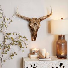 an animal skull mounted on the wall above a table with candles and a vase next to it