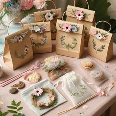 small bags with flowers on them sitting on a table next to cookies and other items