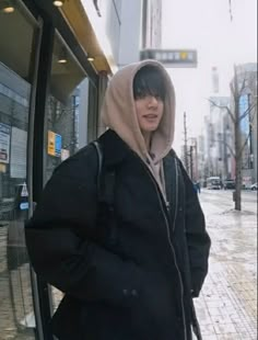 a person standing in front of a bus on a city street wearing a hoodie