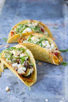 three tacos with various toppings sitting on a table