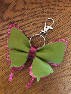 a green and pink bow shaped keychain sitting on top of a wooden table