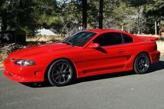 a red sports car parked in front of some trees