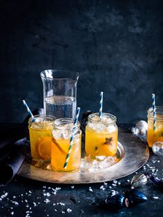 three glasses filled with lemonade on top of a metal tray next to silver spoons