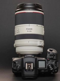 the canon 70 - 200mm lens is sitting on top of another camera's body