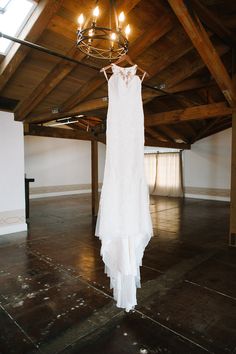 a wedding dress hanging from a chandelier in an empty room with lights on the ceiling