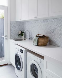 a washer and dryer in a white laundry room with marble backsplash