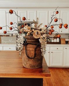 a wooden bucket filled with flowers on top of a kitchen counter next to white cabinets