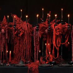 a table topped with lots of candles covered in red yarn