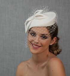 a woman wearing a white veil with a bow on it's head is smiling at the camera