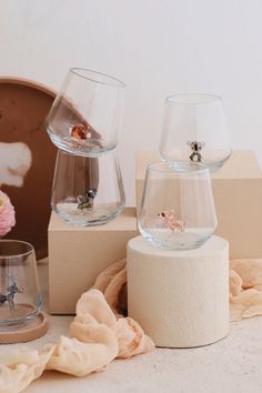 three glass vases sitting on top of a wooden stand next to flowers and cloth