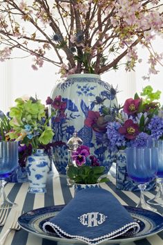 a blue and white table setting with flowers in vases