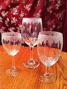 three wine glasses sitting on top of a wooden table