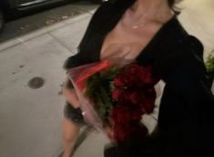 a woman walking down the street holding flowers