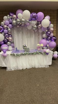 a table topped with purple and white balloons