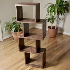 a wooden shelf sitting on top of a hard wood floor next to a potted plant