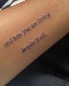 a person with a tattoo on their arm that says and here you are living despite it all