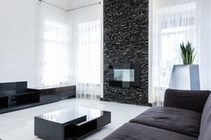 a black and white living room with stone wall behind the couches, coffee table and television