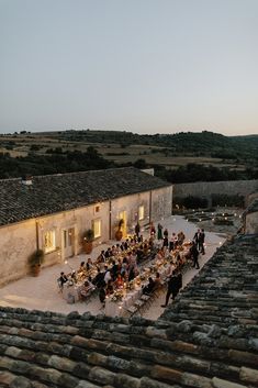 a group of people sitting around a table on top of a stone floored building