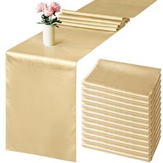 the table runner is gold with pink flowers in it and folded napkins on each side