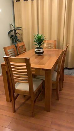 a wooden table with chairs and a potted plant sitting on it's side