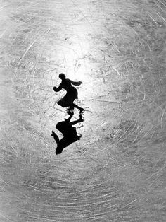 two people skating on an ice rink in the middle of winter, silhouetted against snow