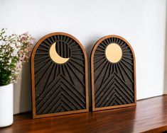 two wooden plaques sitting on top of a shelf next to a vase with flowers in it