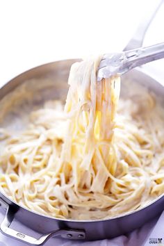 someone is adding cheese to some noodles in a pan