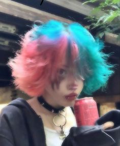 a woman with pink, blue and green hair holding a red cup in her hand