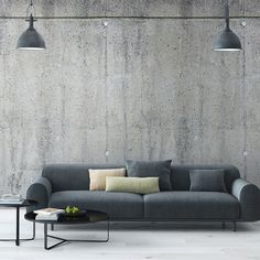 a couch and table in front of a concrete wall with two lamps hanging above it