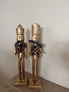 two wooden nutcrackers with black bows on their heads and legs, standing next to each other