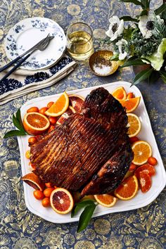 a large piece of meat sitting on top of a white plate covered in orange slices