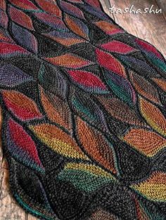 a multicolored knitted blanket sitting on top of a wooden floor