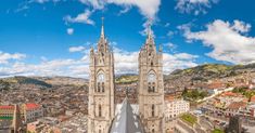 an aerial view of a cathedral in the middle of a city with mountains and buildings behind it