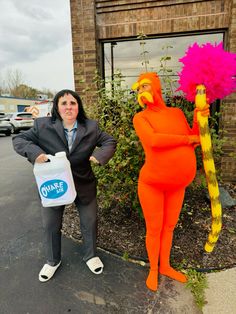 a woman standing next to a giant orange and pink character holding a water jug in front of a building