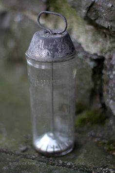 an old metal blender sitting next to a stone wall