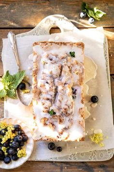 a piece of bread with icing and blueberries next to it on a plate